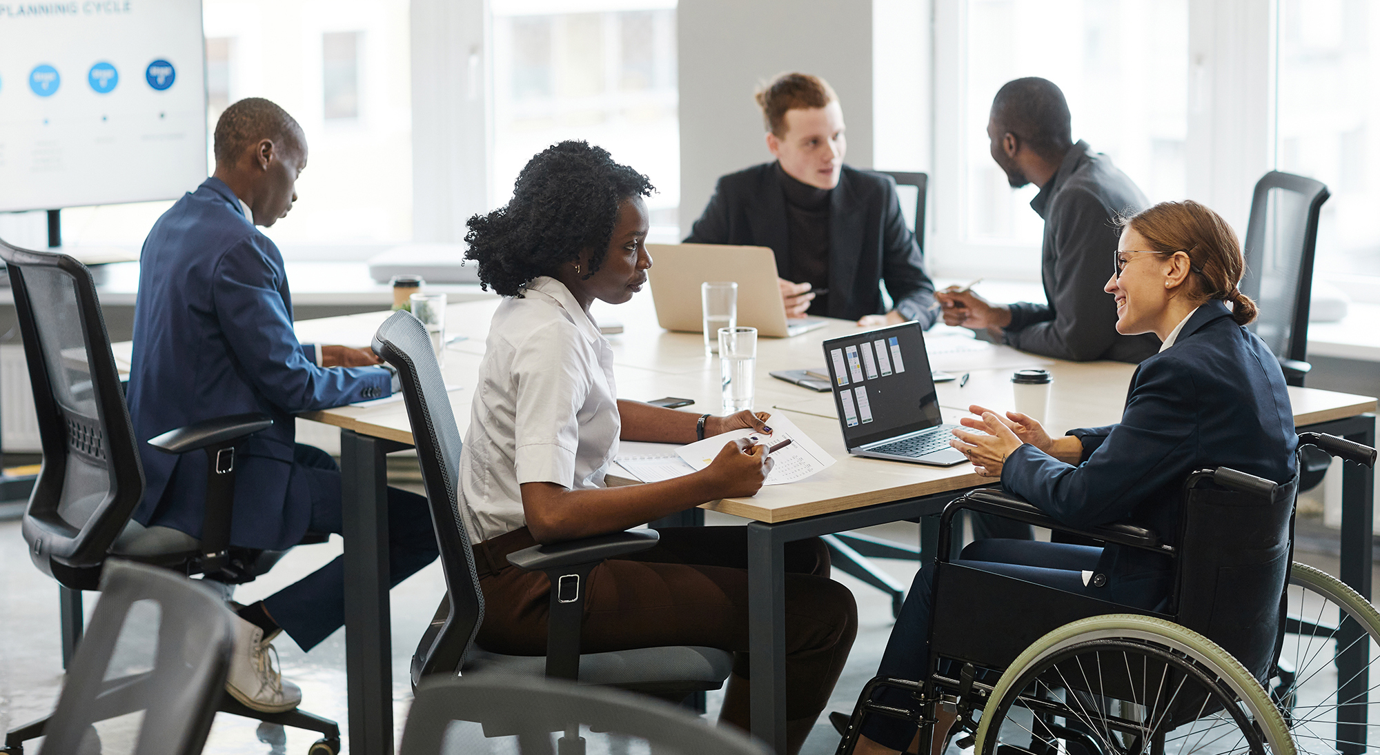 Portrait of successful businesswoman using wheelchair while speaking to employee in meeting